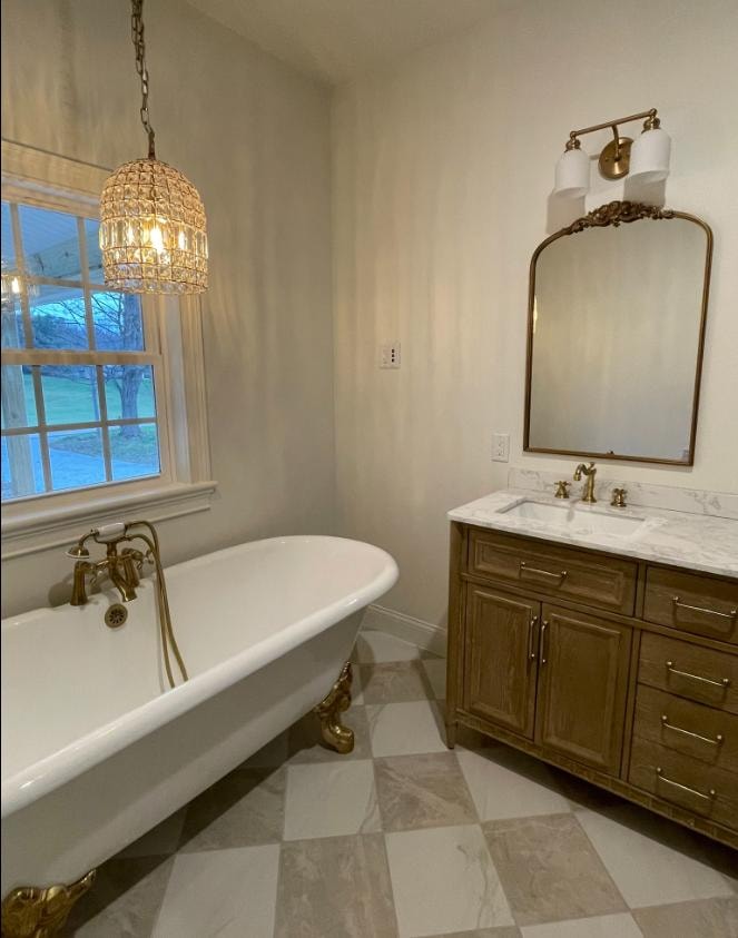 Bathroom remodel with clawfoot tub, gold fixtures, and crystal chandelier