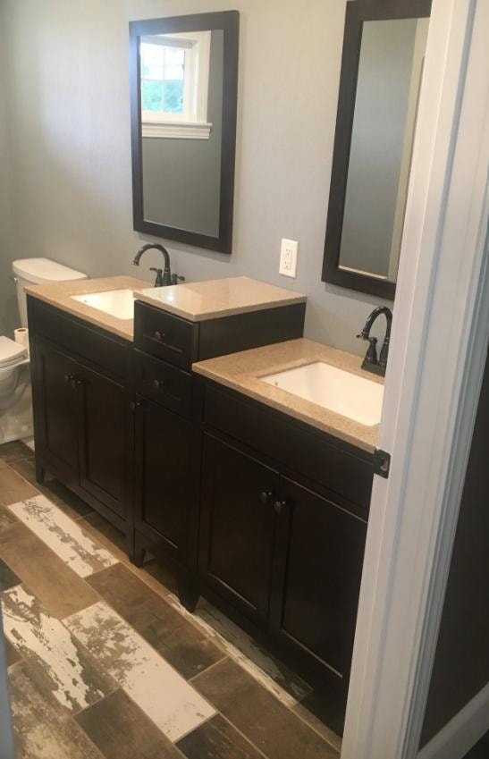 Bathroom remodel with dark wood double vanity, granite countertop, and framed mirrors