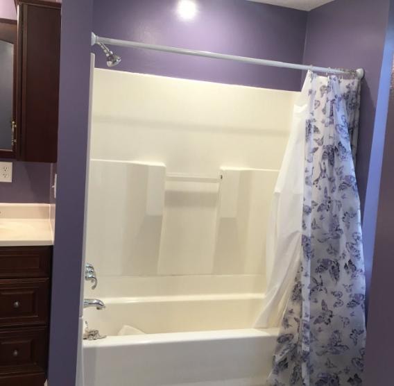 Bathroom remodel with tub surround, dark wood cabinetry, and fresh paint
