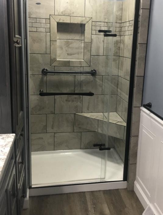 Bathroom shower remodel with large format tile, built-in niche, corner seat, and black fixtures