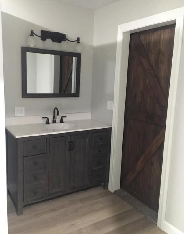 Bathroom remodel with dark wood vanity, white quartz countertop, black fixtures, and custom barn door