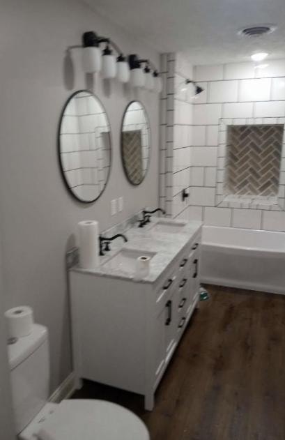 Bathroom remodel with double vanity, round mirrors, and herringbone tile niche