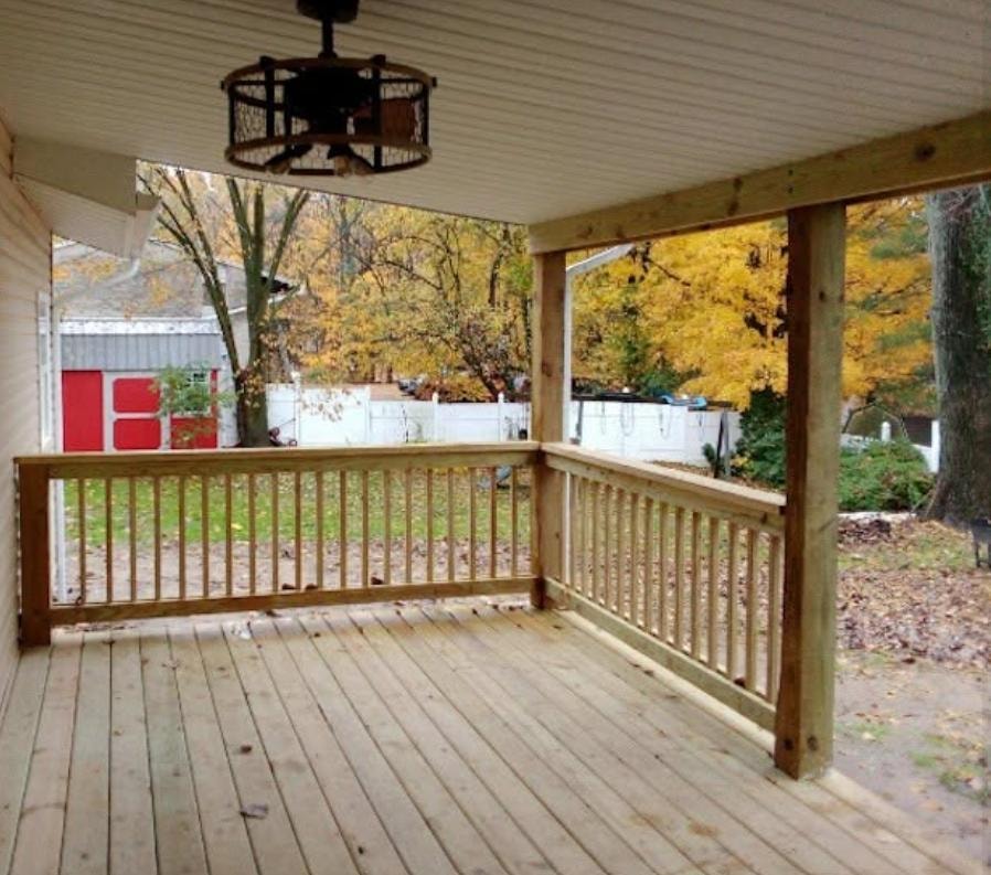New covered porch addition with wood decking, railings, and ceiling fan