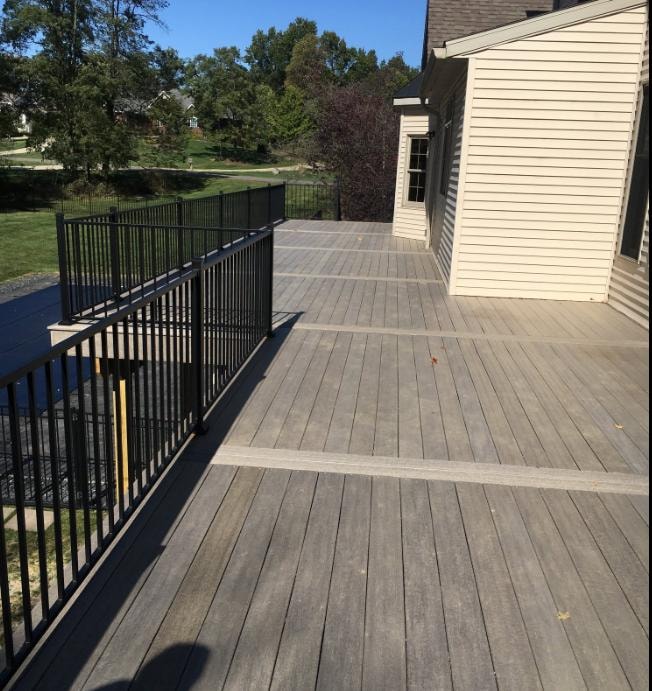 Large composite deck build with gray decking, black aluminum railing, and step access