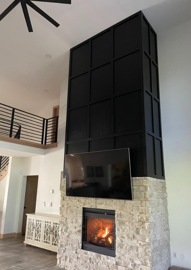 Two-story fireplace feature wall with black panel surround and stone base