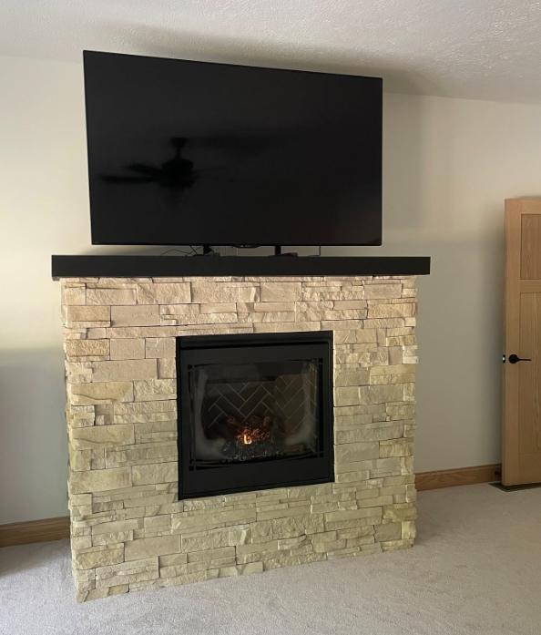 Stone fireplace with TV mount and wood mantel