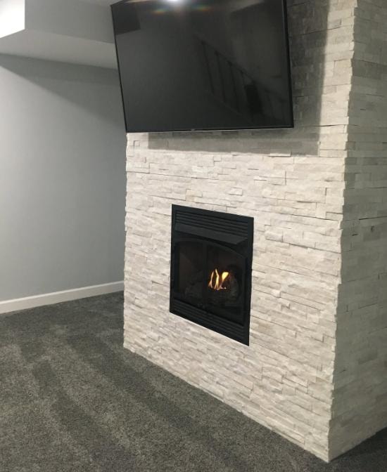 White stacked stone fireplace with gas insert and wall-mounted TV