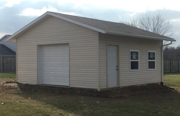 New detached garage build with vinyl siding, overhead door, and entry door