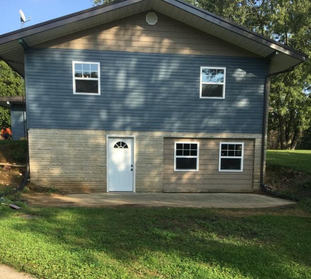 Home addition with blue and tan vinyl siding, new windows, and concrete patio
