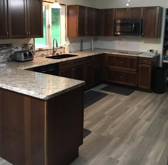 Kitchen remodel with dark wood cabinetry, granite peninsula countertop, and new LVP flooring