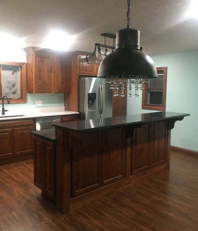 Kitchen remodel with dark wood cabinetry, black island, and stainless appliances