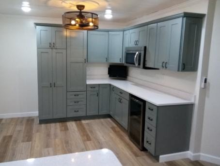 Kitchen remodel with sage green shaker cabinets, white quartz countertops, and hardwood floors