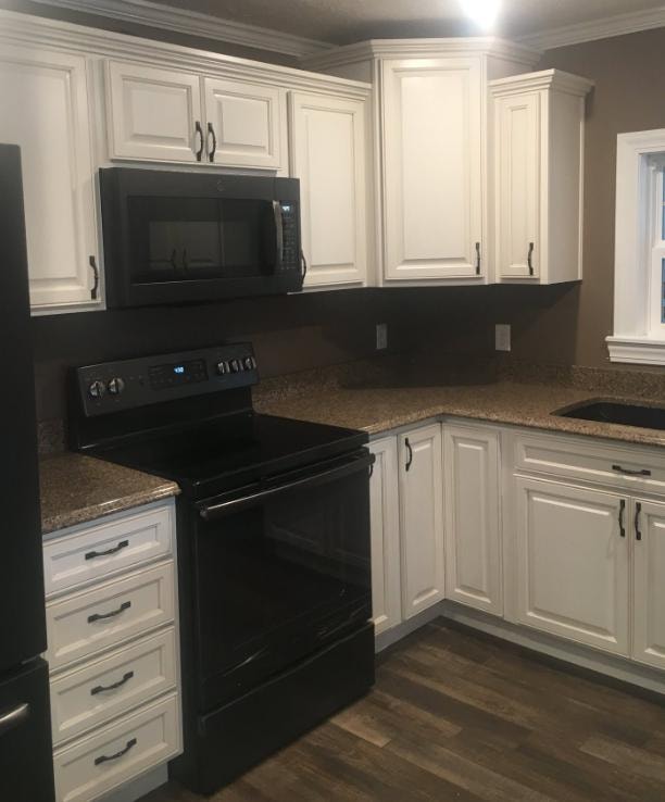 Kitchen remodel with white raised-panel cabinets, granite countertops, and black appliances