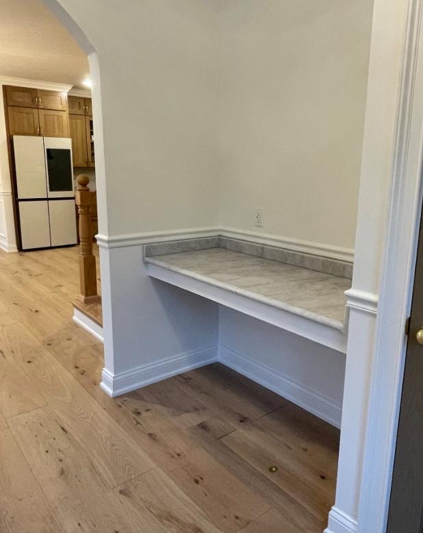 Custom built-in mudroom bench with marble top, white trim, and hardwood flooring